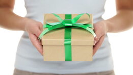 Picture of a lady holding a box with a green bow and presenting it to you.